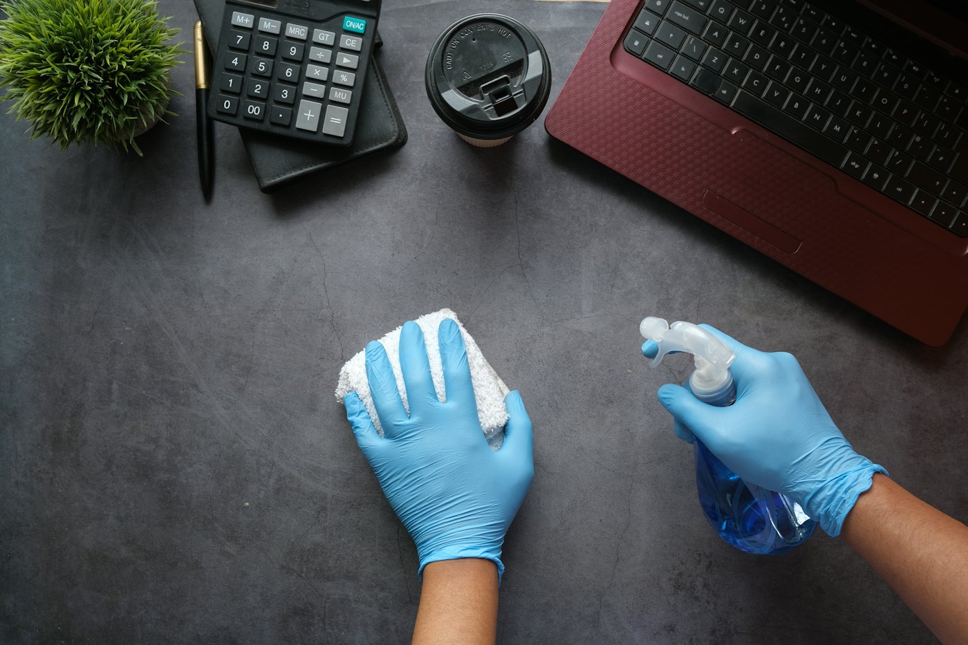 Gloved cleaner sanitizing an office desk and workstation in Edmonton